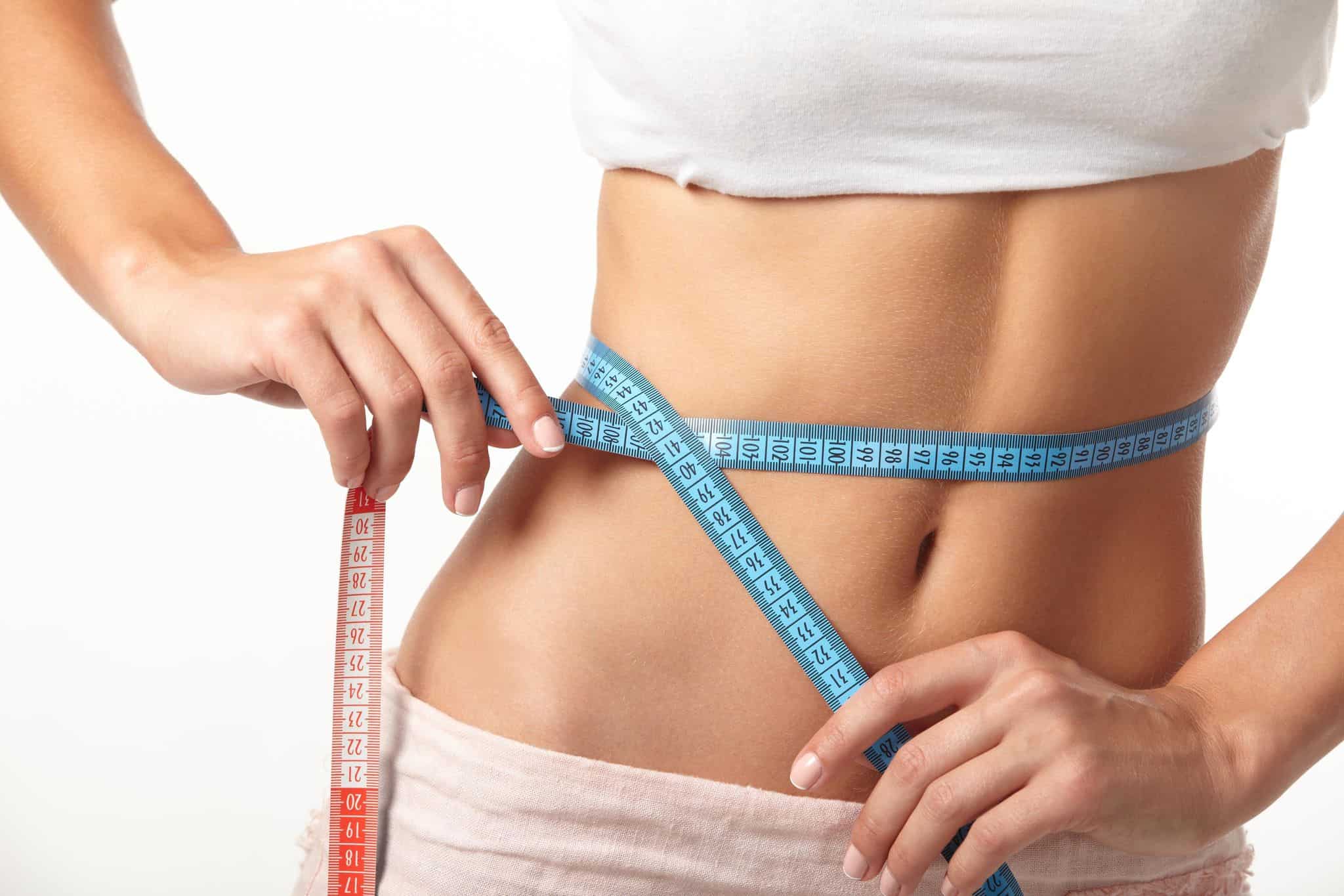 Patient measuring waist as part of a doctor-supervised weight loss plan